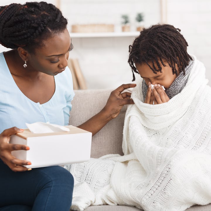 Seasonal Infectious Disease, Epidemic. African girl sneezing, having runny nose. Black mom with napk...
