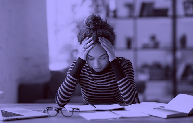 Stressed young afro american woman holding head in hands and feeling demotivated while sitting at he...