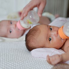 mother feeding two twins from the bottle