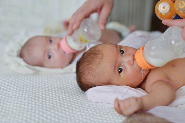 mother feeding two twins from the bottle