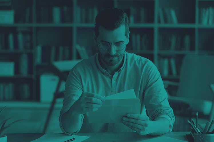 Serious businessman sit at workplace office desk holding envelope.