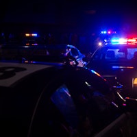 Blue and red police lights on squad cars during a night time traffic stop, with space for text on th...