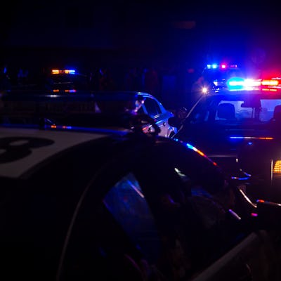 Blue and red police lights on squad cars during a night time traffic stop, with space for text on th...