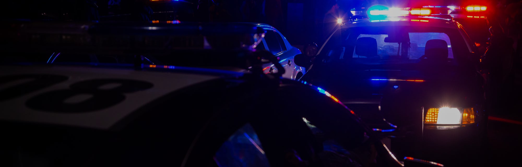 Blue and red police lights on squad cars during a night time traffic stop, with space for text on th...