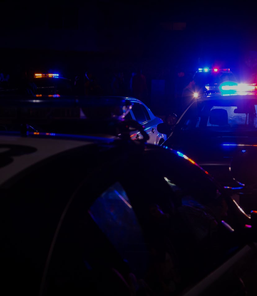 Blue and red police lights on squad cars during a night time traffic stop, with space for text on th...