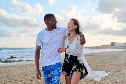 Young happy couple walking on the beach and holding hands