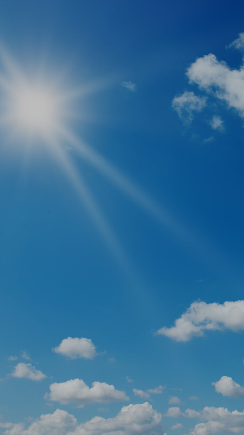 Bright sun on beautiful blue sky with white fluffy clouds.