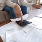Close up busy woman using calculator, renter checking bills, planning budget, sitting at desk with f...