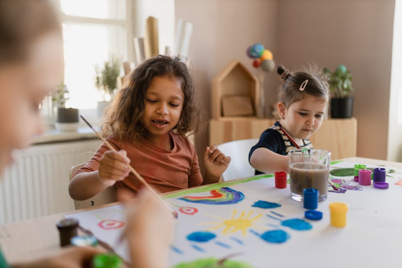 Happy little girls painting picture during creative art and craft class at school in an article of c...