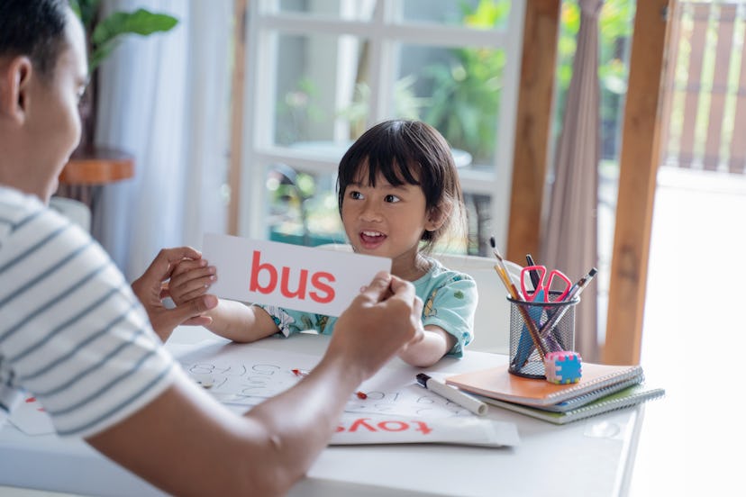 dad showing flash card with simple word to help her daughter to read in an article about what are si...