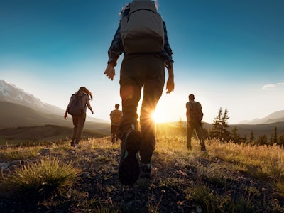 Group of sporty people walks in mountains at sunset with backpacks. Altai mountains, Siberia, Russia...