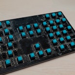Dirty surface of a disassembled mechanical keyboard with blue switches. Dirt, hair and food particle...