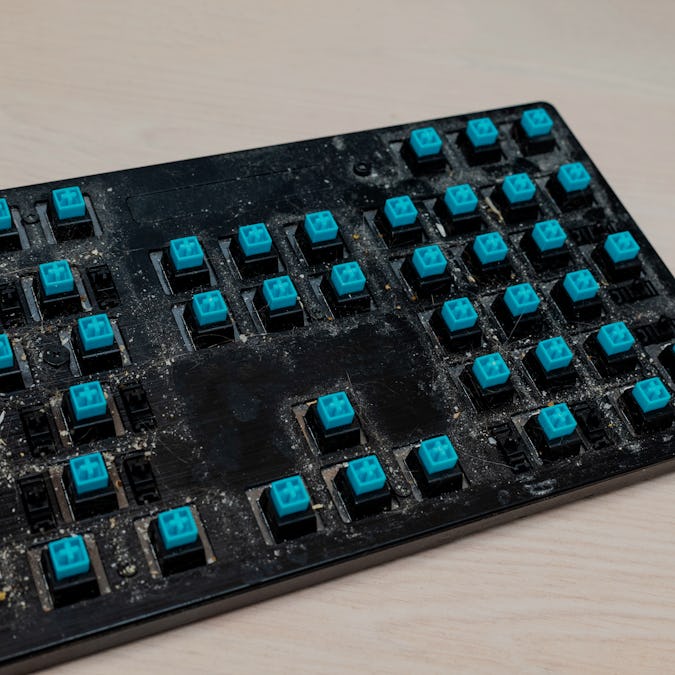 Dirty surface of a disassembled mechanical keyboard with blue switches. Dirt, hair and food particle...