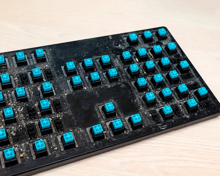 Dirty surface of a disassembled mechanical keyboard with blue switches. Dirt, hair and food particle...