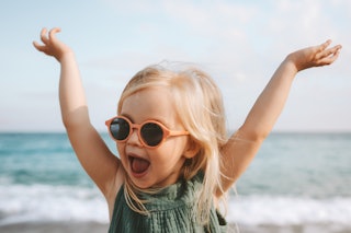 Funny kid girl playing outdoor surprised emotional child in sunglasses 3 years old baby raised hands...