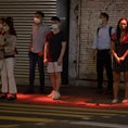 A red light is projected onto pedestrians waiting to cross a road as a novel safety warning in Hong ...