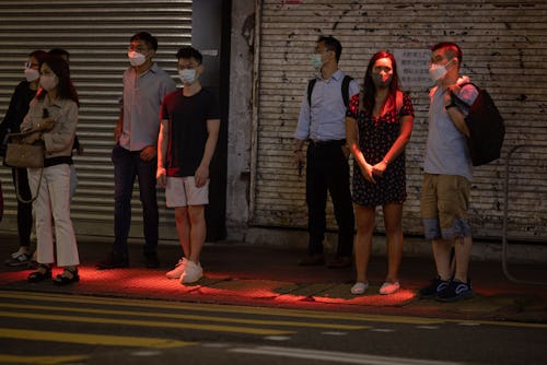 A red light is projected onto pedestrians waiting to cross a road as a novel safety warning in Hong ...
