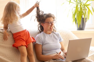 Distant home office during lockdown.Little daughter bothering interfering mother freelancer working ...
