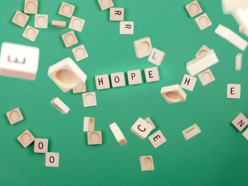 green background with scrabble pieces with the word hope and pieces falling