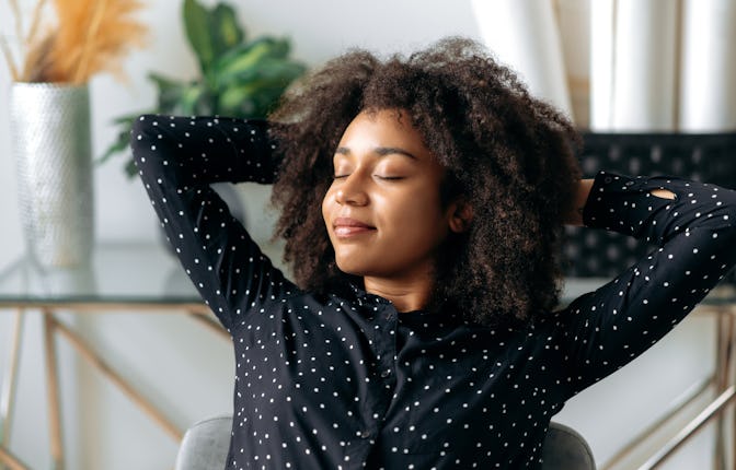 Close-up of a charming, calm, dark-skinned curly haired woman, manager, financial director, sitting ...