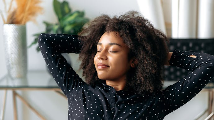 Close-up of a charming, calm, dark-skinned curly haired woman, manager, financial director, sitting ...