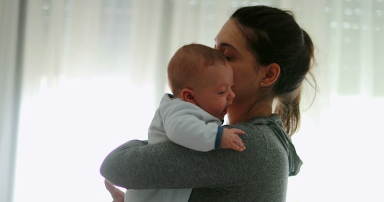 Casual real life mom consoling crying newborn baby son at home