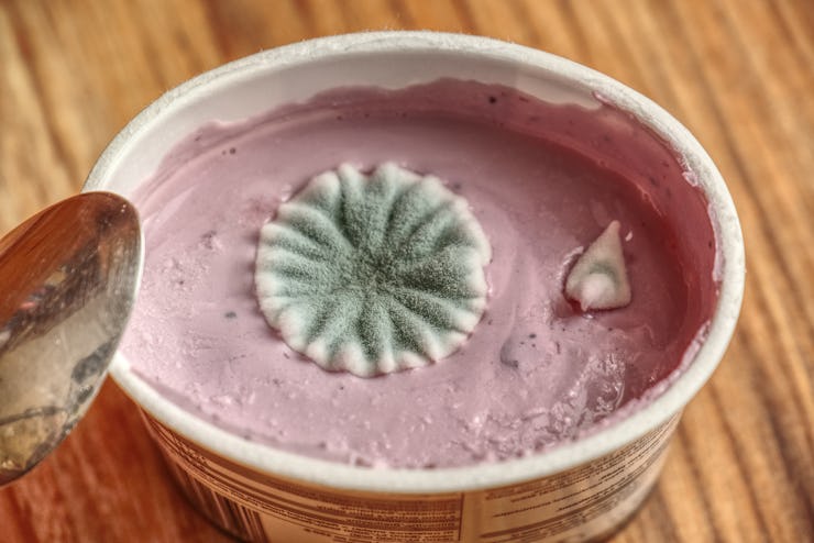 Moldy yogurt on a wooden table background. Poisoning breakfast