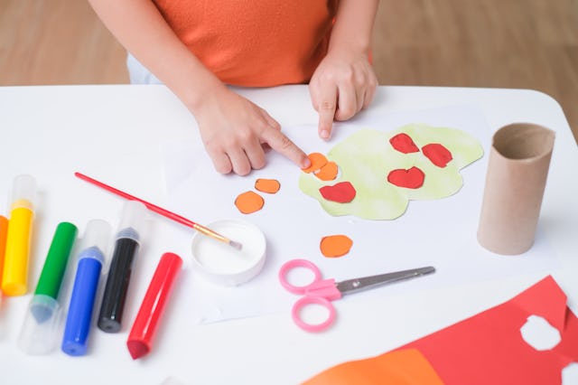 Top view of little 3 years old toddler boy enjoy using glue doing arts at home, Fun paper and glue c...