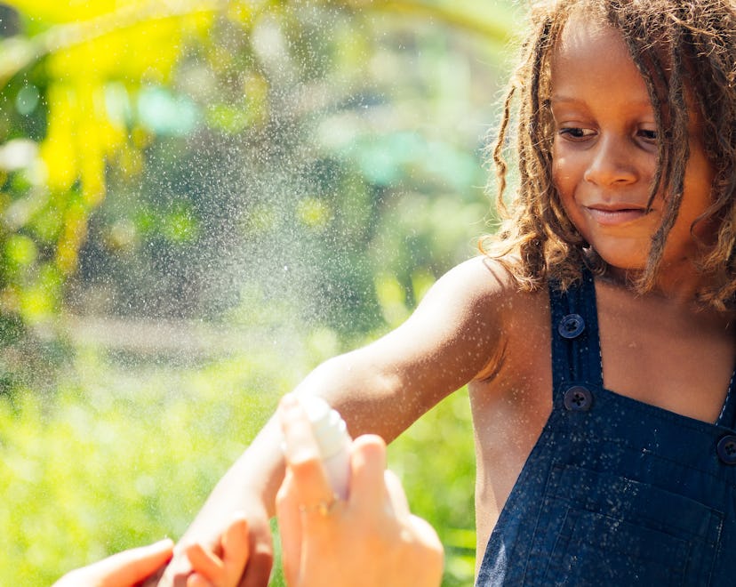 Mowgli indian boy with dreadlocks hair hiding holding mosquito spray in tropics green forest backgro...