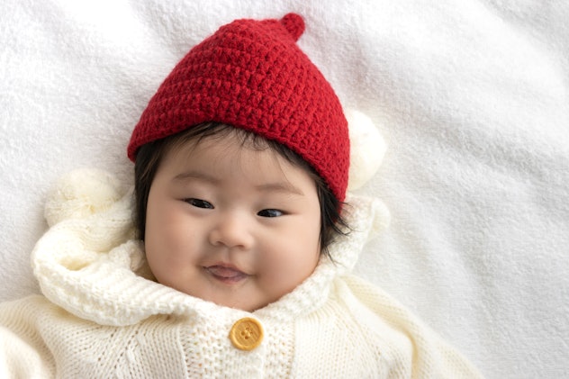Baby's face in white sweater and red knit hat, clearly very excited to have such a great baby girl n...
