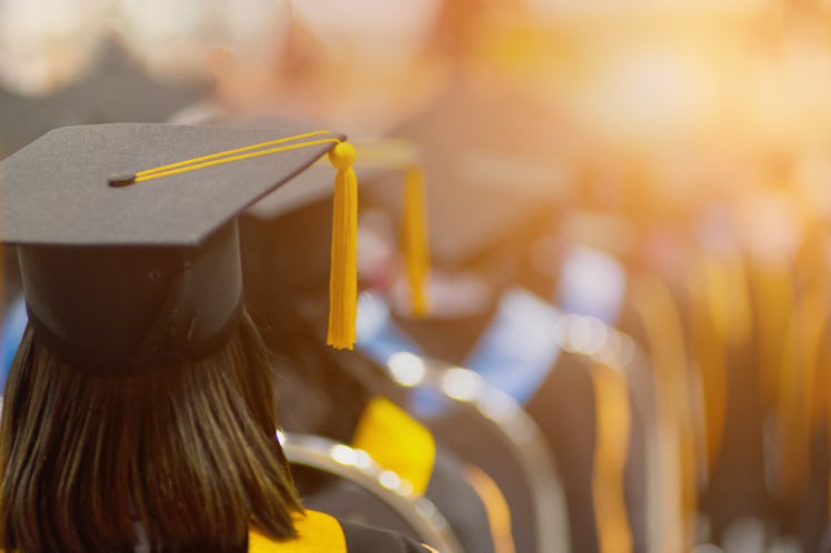 Rear view selective focus of the university graduates crowded in the graduation ceremony. The gradua...