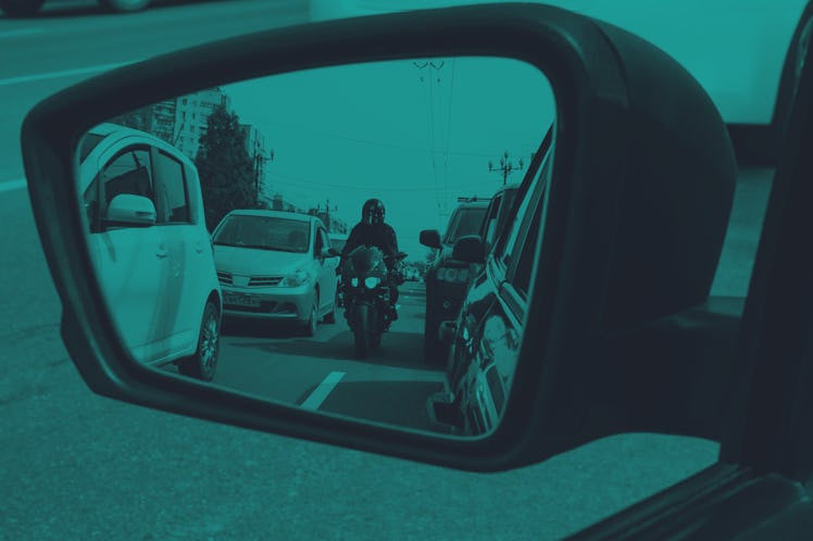 A red, sporty, motorcycle moves between the lane, dangerously close to cars.