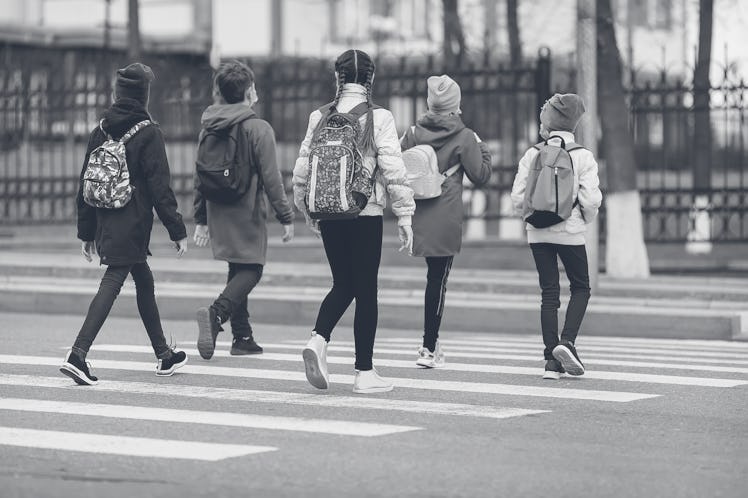 School children cross the road in medical masks. Children go to school