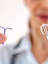 Female doctor holding two knd of intra utreine devine for birth control