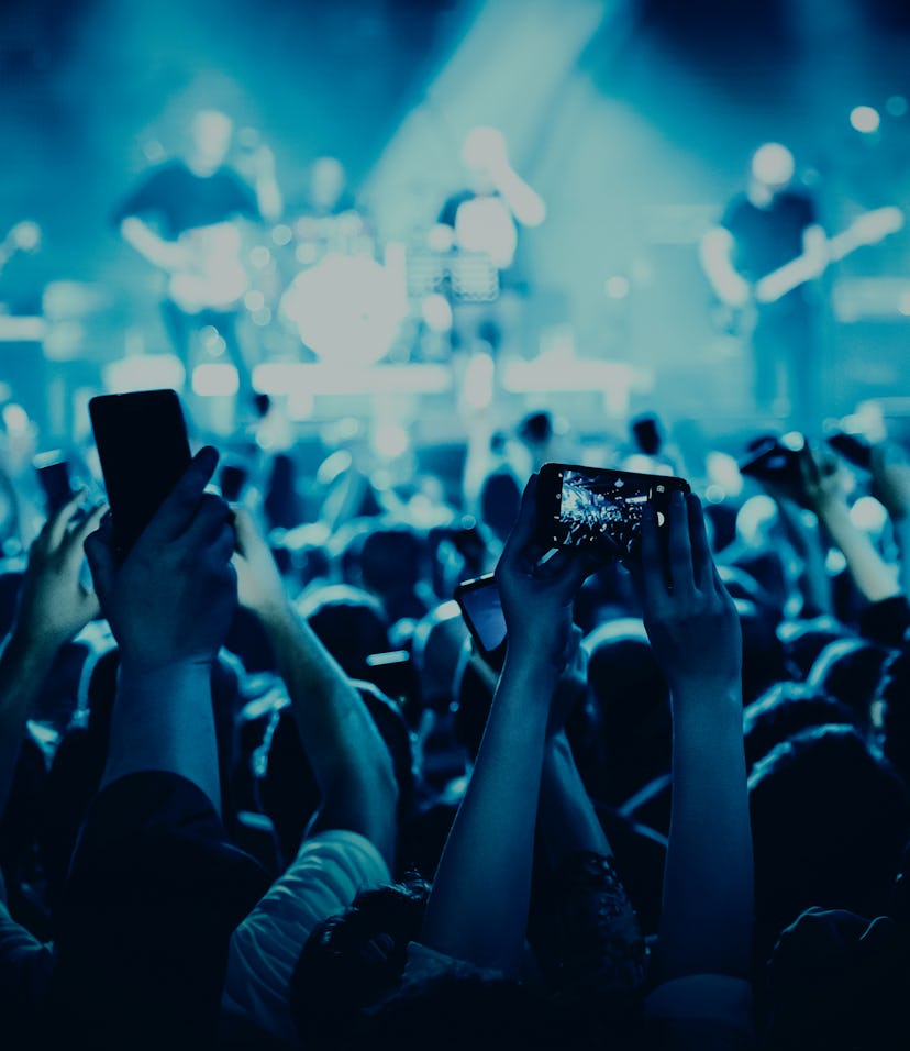 A lot of hands with the smartphone turned on to record or take pictures during the live concert