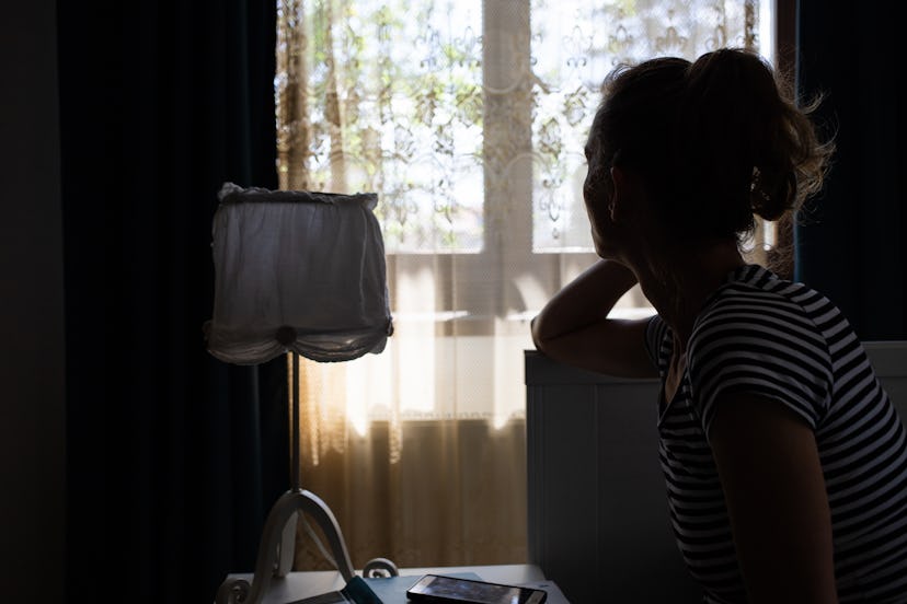 silhouette of woman by bedside holding her head  in an article about sex and intimacy issues