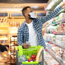 African American Man Doing Grocery Shopping In Supermarket, Wearing Protective Face Mask, Buying Foo...