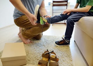 Online shopping for baby and kids. Father helping fitting shoes for his child at home. Free of charg...