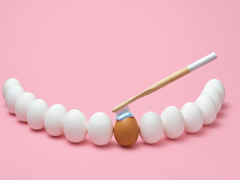 Concept for oral hygiene with a wooden toothbrush, toothpaste, and several eggs simulating the human...