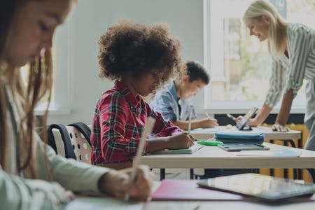 Three students work on their school work while sitting at separate desks