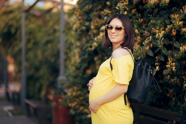 Happy Pregnant Woman Wearing Sunglasses Carrying Backpack. Mother to be talking a walk in the park ...