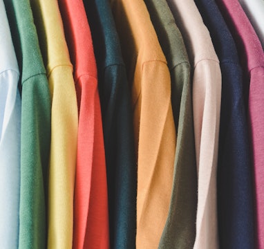 close up a collection of colorful t-shirts hanging on a clothes hanger in closet or clothing rack