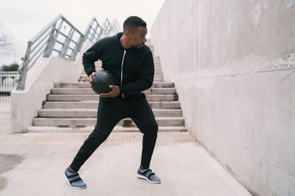 Portrait of an athletic man doing wall ball exercise outdoors. Sport and healthy concept.