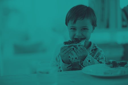 A cute little boy eating toast with jam.