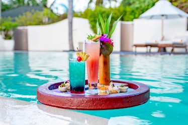 served floating tray in swimming pool with drinks and snacks on tropical island resort in Maldives, ...