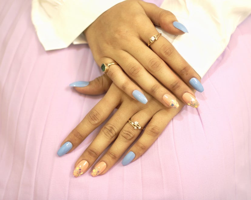 Nude and sky blue colored nail art with glitter touch on extended nails closeup on a light pink back...