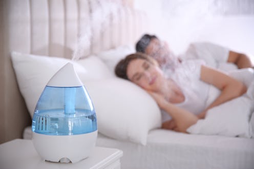 Couple sleeping in bedroom with modern air humidifier