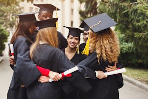 Group of multietnic students hugging on their graduation day at university, copy space. Education, q...