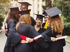 Group of multietnic students hugging on their graduation day at university, copy space. Education, q...