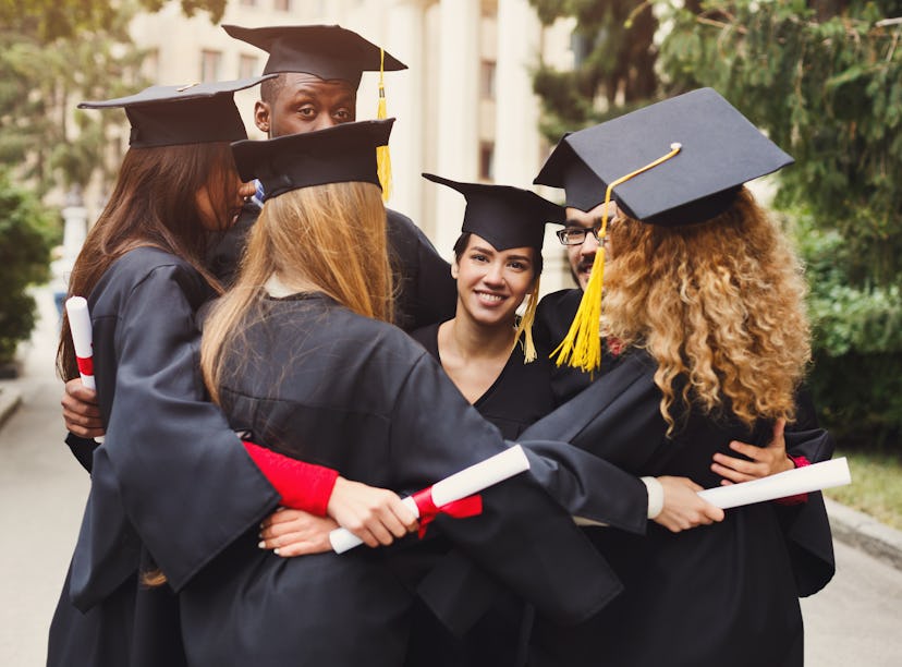 Group of multietnic students hugging on their graduation day at university, copy space. Education, q...